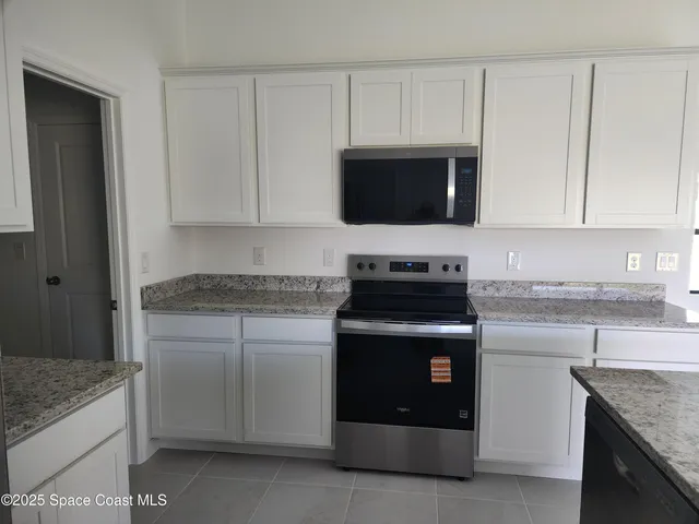 a kitchen with stainless steel appliances granite countertop a refrigerator a stove a sink a microwave and white cabinets