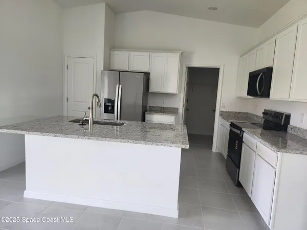 a living room with stainless steel appliances furniture a refrigerator and a sink