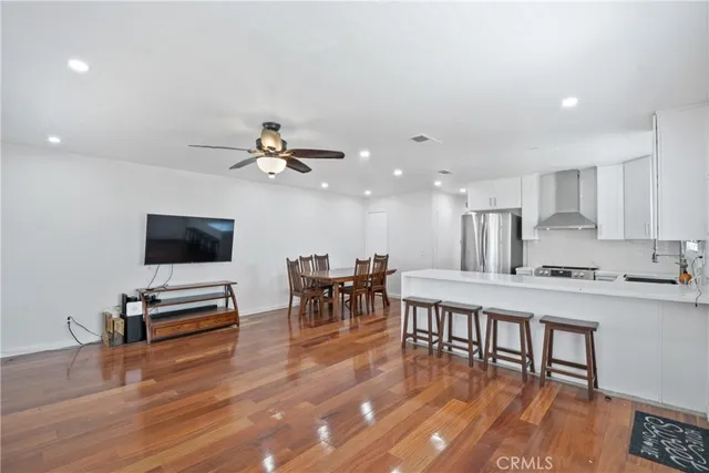 a living room with stainless steel appliances furniture and a flat screen tv