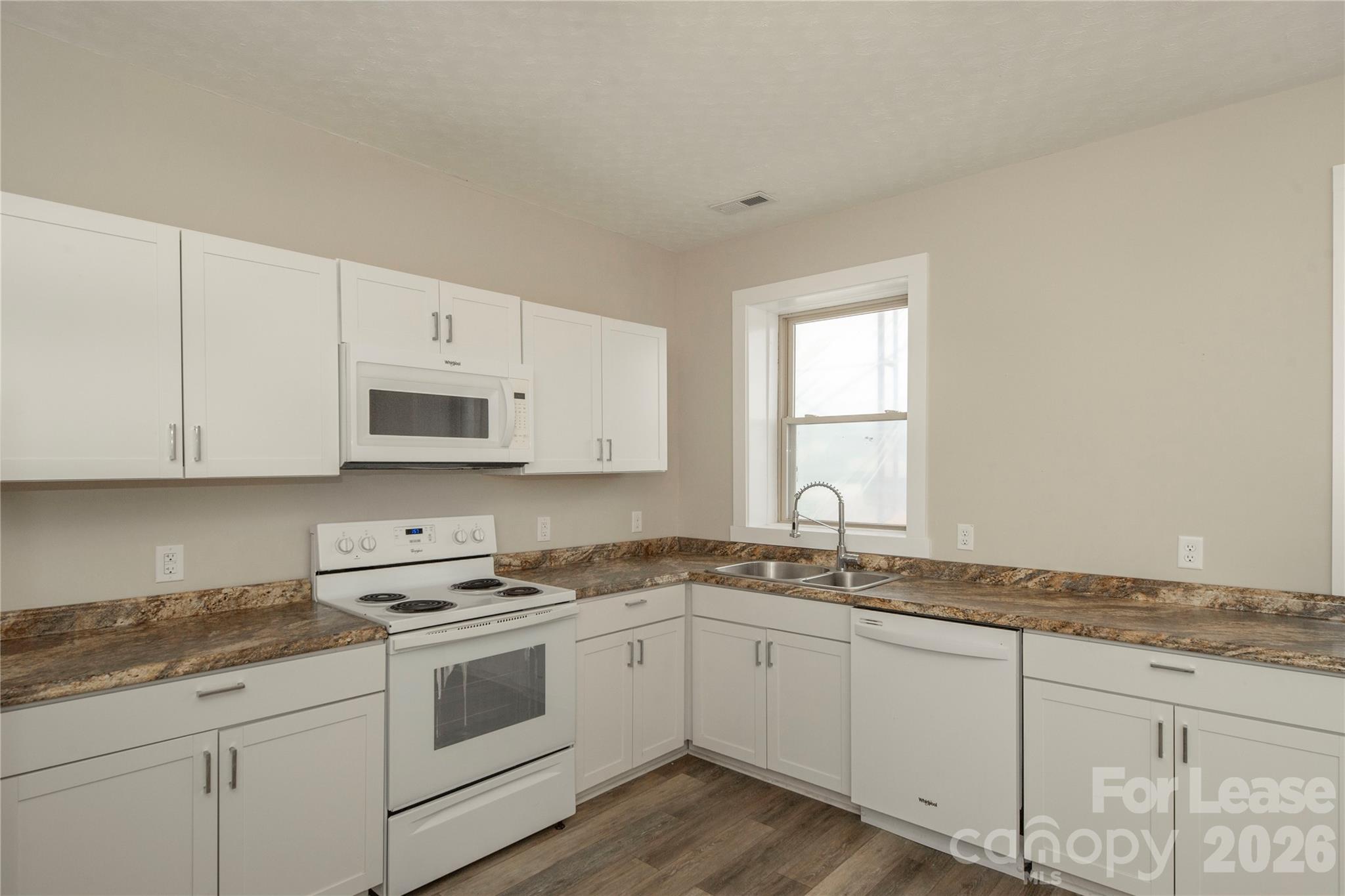 212 South Broad Street Brevard, NC 28712 - Photo 2 of 12 a kitchen with granite countertop white cabinets and white appliances