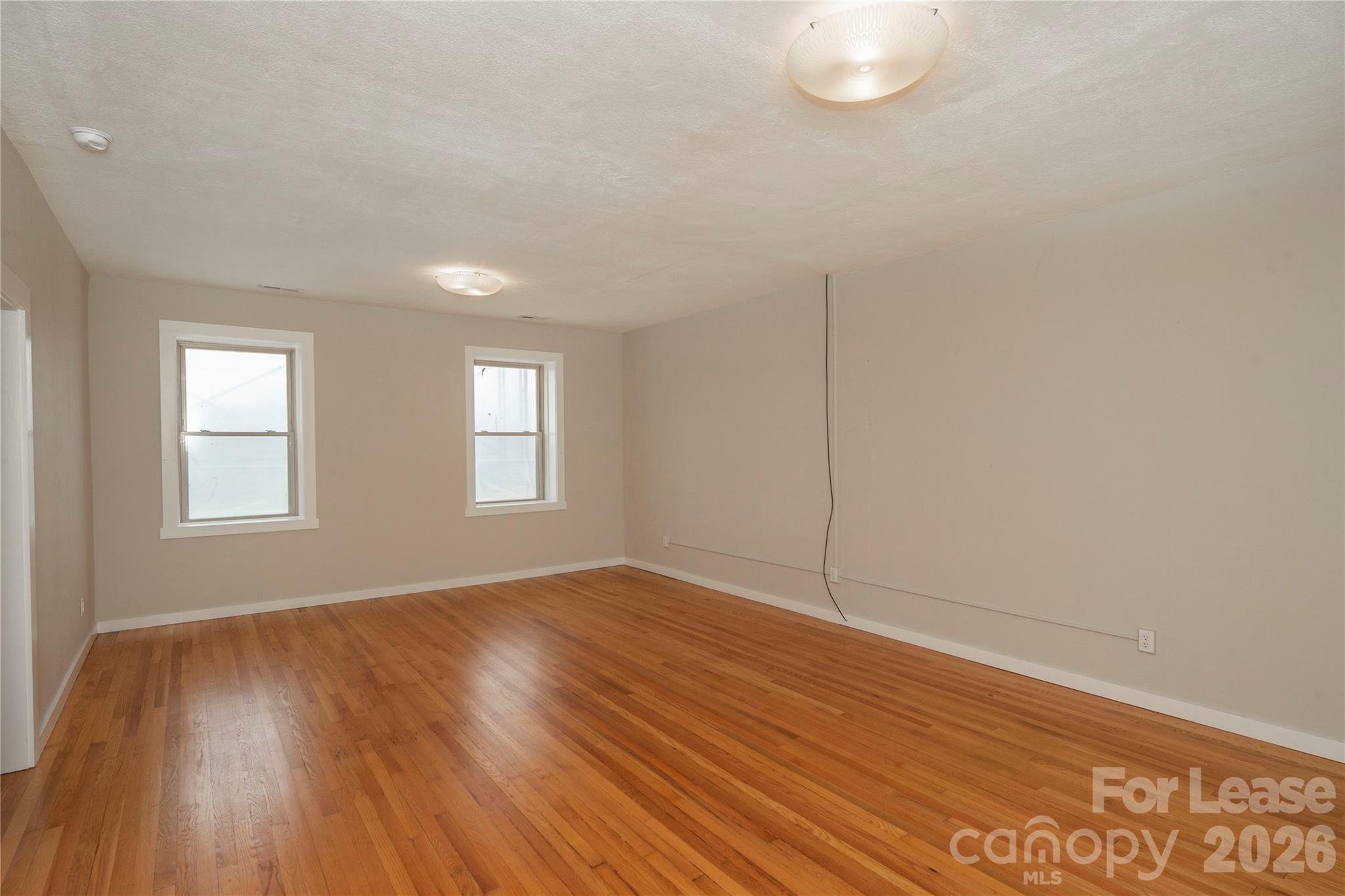 212 South Broad Street Brevard, NC 28712 - Photo 3 of 12 an empty room with wooden floor and windows