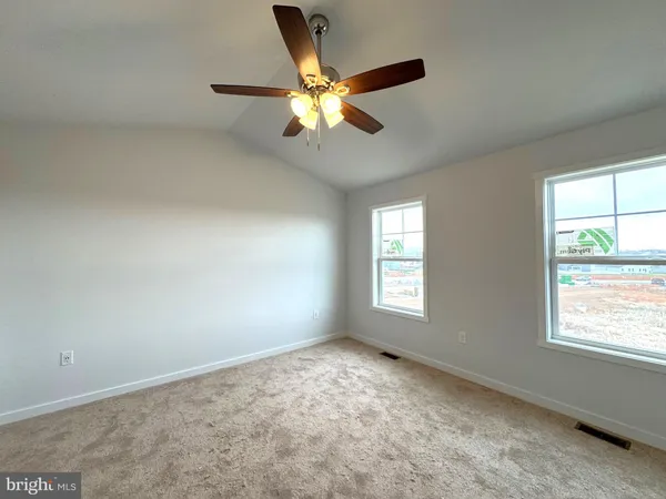 a view of an empty room with window and chandelier fan