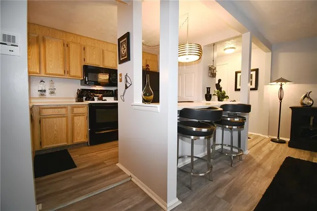 a kitchen with stainless steel appliances kitchen island granite countertop a refrigerator a stove top oven a sink dishwasher and white cabinets with wooden floor