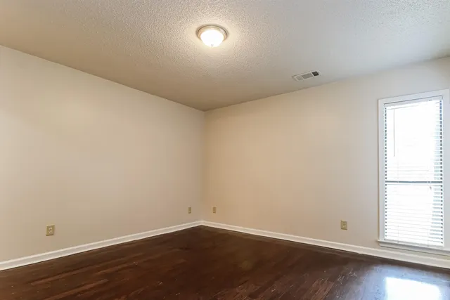 an empty room with wooden floor and ceiling fan