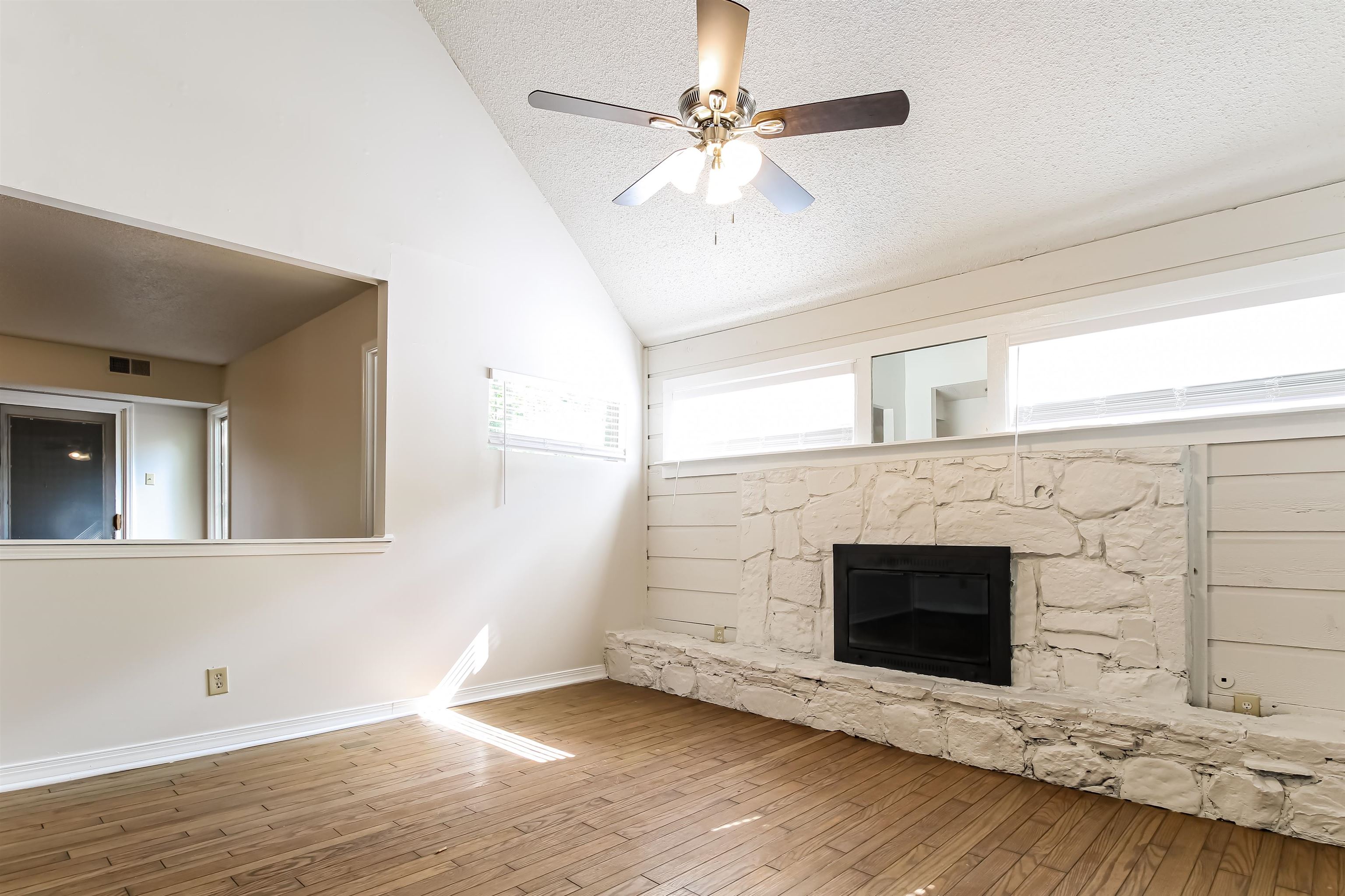 8661 Roundtree Place Memphis, TN 38016 - Photo 4 of 17 an empty room with windows fireplace and fan