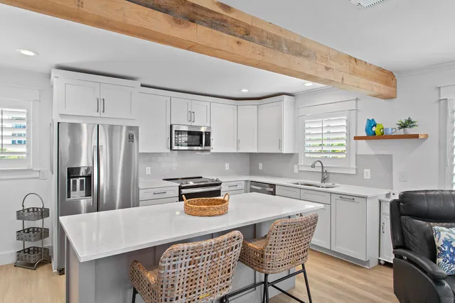 a kitchen with stainless steel appliances granite countertop a sink a stove a refrigerator cabinets a dining table and chairs