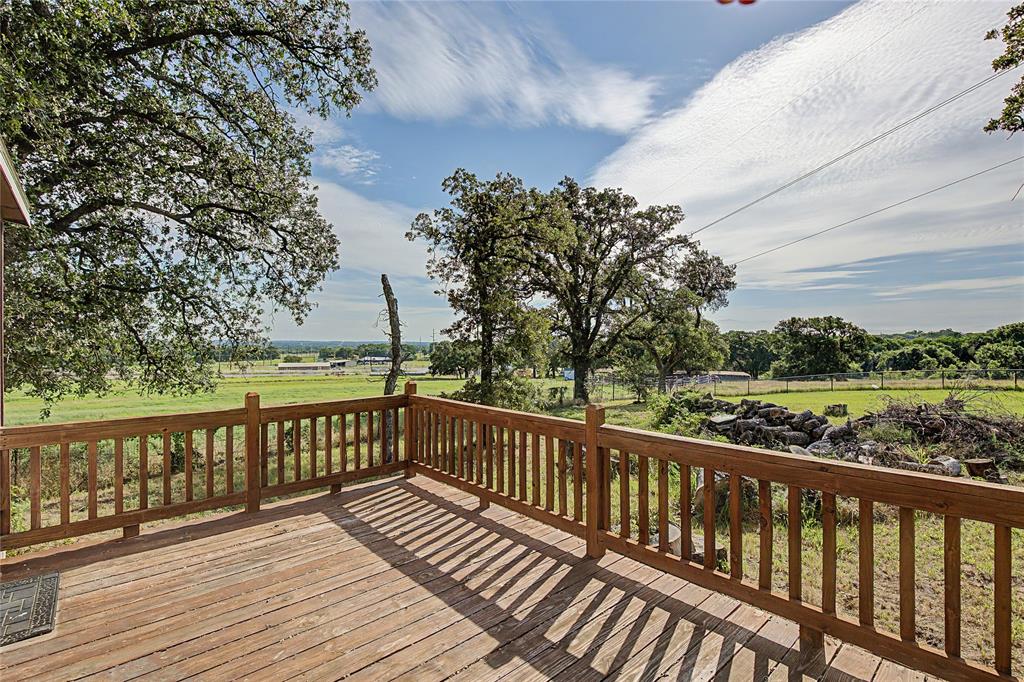 177 New Highland Road Springtown, TX 76082 - Photo 32 of 40 Expansive wood-finish deck with vertical spindle railing overlooking a verdant landscape