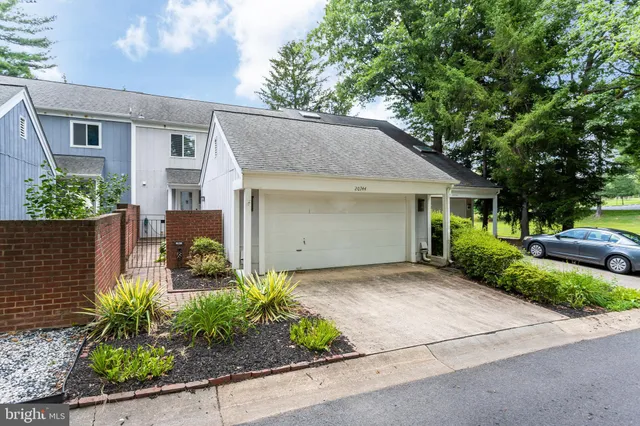 a front view of a house with a garden and lake view