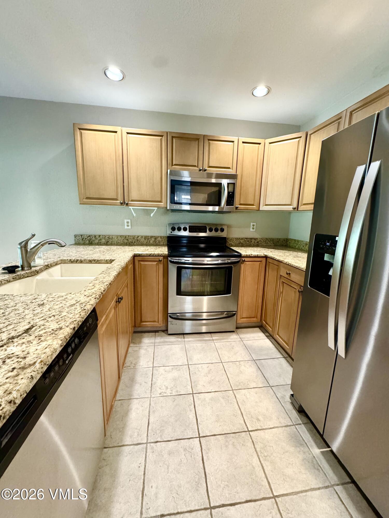 3921 Big Horn Road, Unit 3B Vail, CO 81657 - Photo 9 of 16 a kitchen with stainless steel appliances granite countertop a sink stove and refrigerator