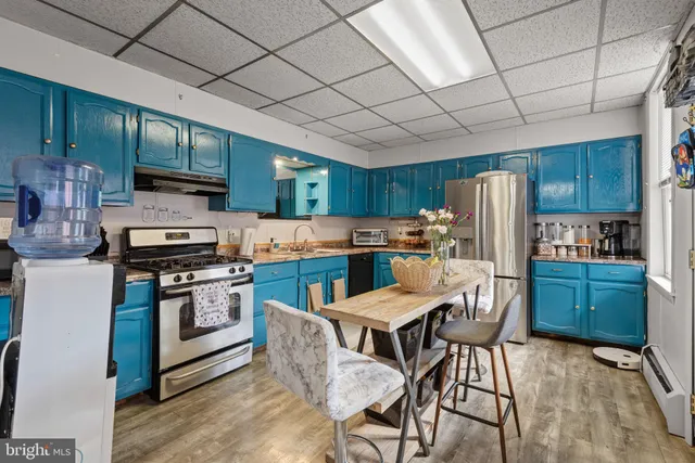 a kitchen with stainless steel appliances granite countertop a stove a refrigerator a sink dishwasher a dining table and chairs with wooden cabinets