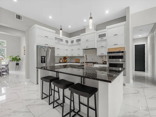 a kitchen with stainless steel appliances a sink a stove a refrigerator and cabinets