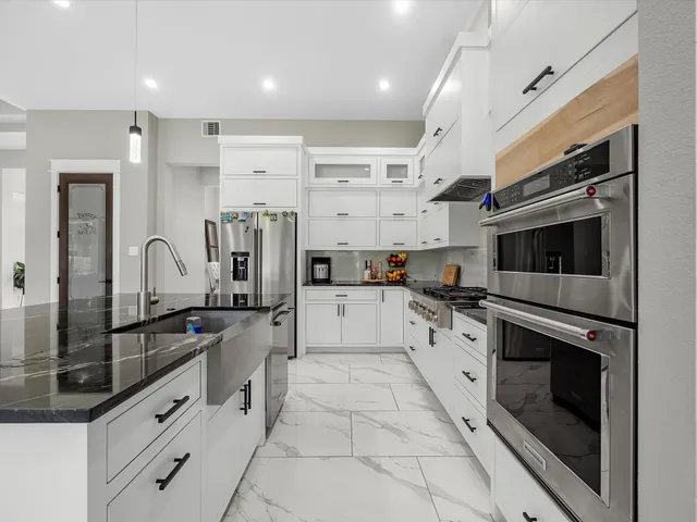 a large kitchen with stainless steel appliances granite countertop a stove and a sink