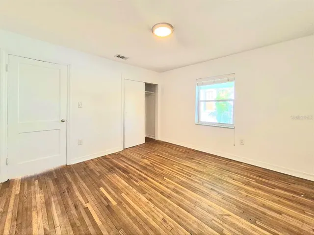 a view of empty room with wooden floor and fan