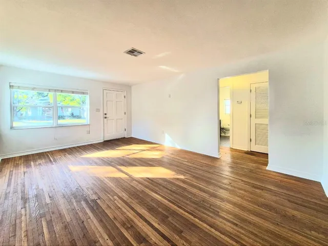 an empty room with wooden floor and windows