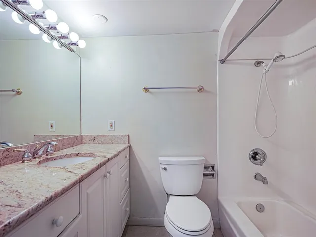 a bathroom with a granite countertop sink a toilet and shower