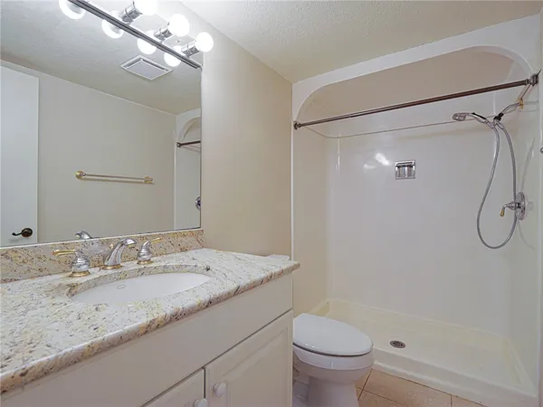 a bathroom with a granite countertop sink a toilet and shower