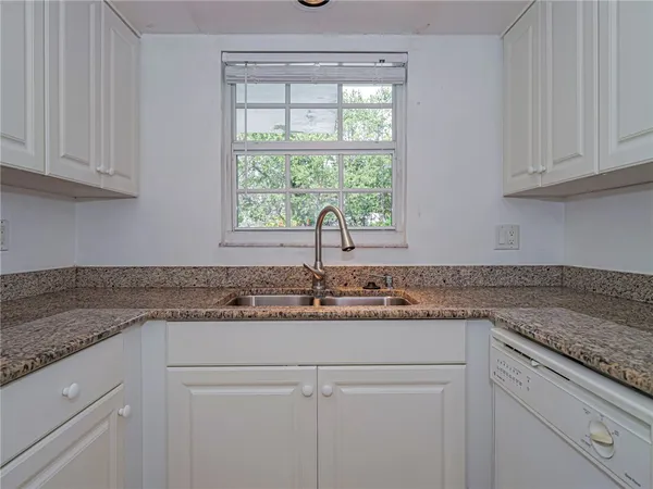 a kitchen with granite countertop white cabinets and a window