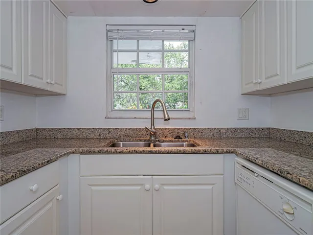 a kitchen with granite countertop white cabinets and a window