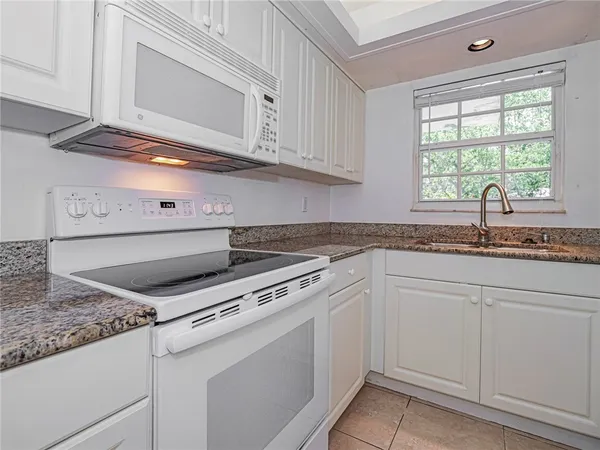 a kitchen with granite countertop white cabinets and white appliances