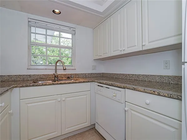 a kitchen with granite countertop white cabinets and a sink