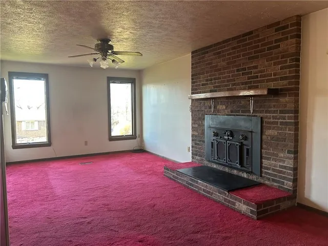 an empty room with windows and fireplace