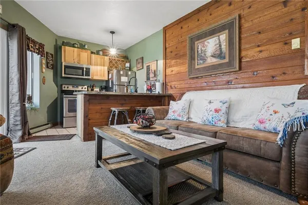 a living room with stainless steel appliances furniture a fireplace and a flat screen tv
