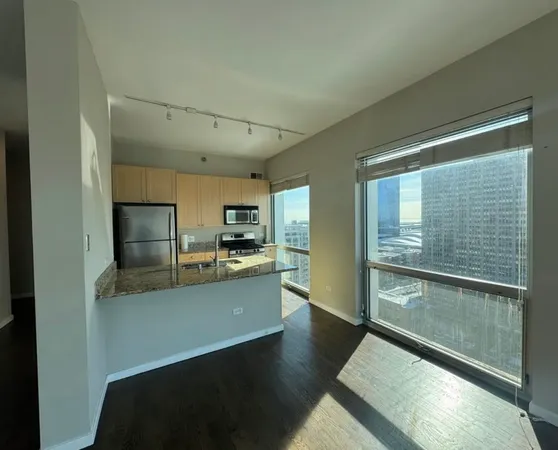 a kitchen with stainless steel appliances granite countertop a refrigerator a stove and a sink with wooden floor