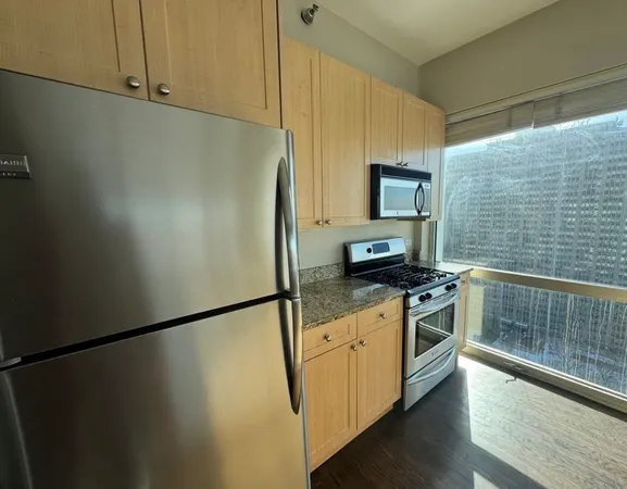 a kitchen with stainless steel appliances granite countertop a refrigerator a stove and a sink