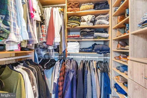 a view of walk in closet with clothes and shoes