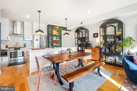 a living room with fireplace a table and kitchen view