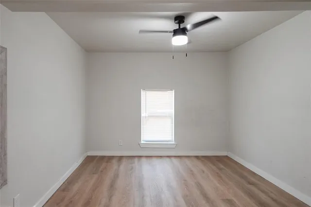 an empty room with a window and a fan