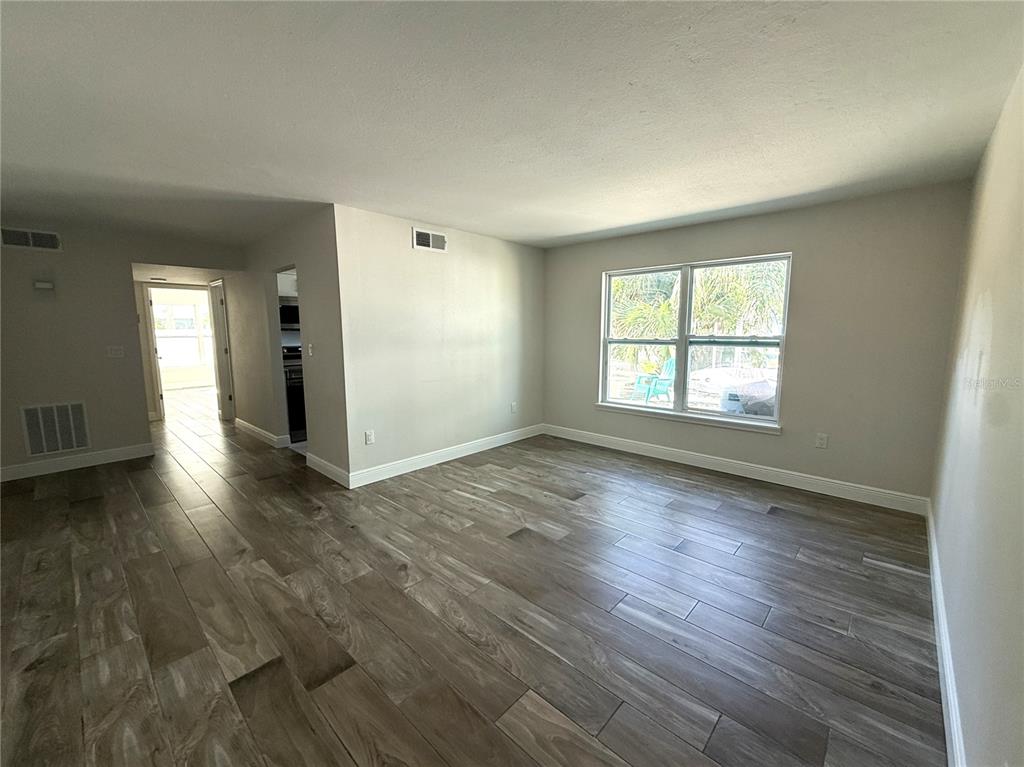 14120 Palm Street, Unit 103 Madeira Beach, FL 33708 - Photo 2 of 19 an empty room with wooden floor and windows