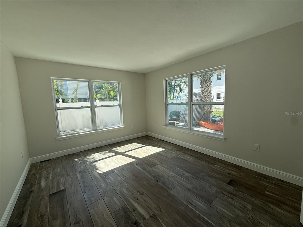 14120 Palm Street, Unit 103 Madeira Beach, FL 33708 - Photo 6 of 19 an empty room with wooden floor and windows
