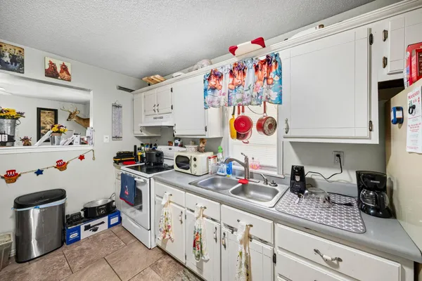a kitchen with granite countertop lots of clutter and refrigerator