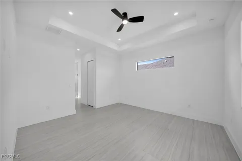 an empty room with ceiling fan and window