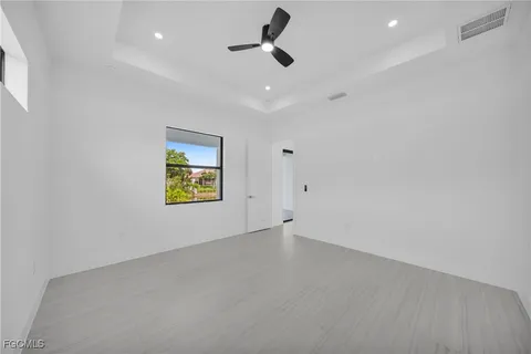 an empty room with ceiling fan and window