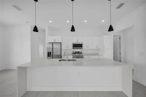 a large kitchen with stainless steel appliances a large counter top a stove and a window