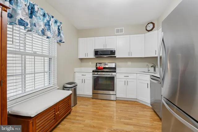 a kitchen with stainless steel appliances granite countertop a stove and white cabinets