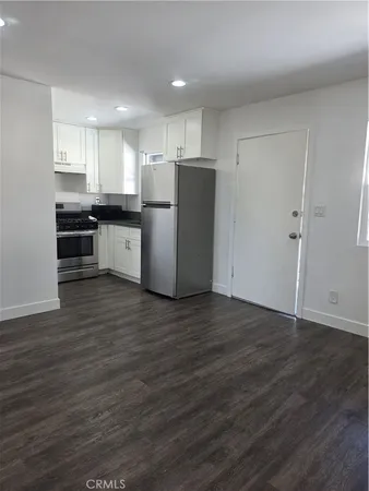 a kitchen with stainless steel appliances wooden floors and white walls