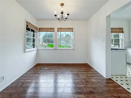 an empty room with wooden floor chandelier and windows