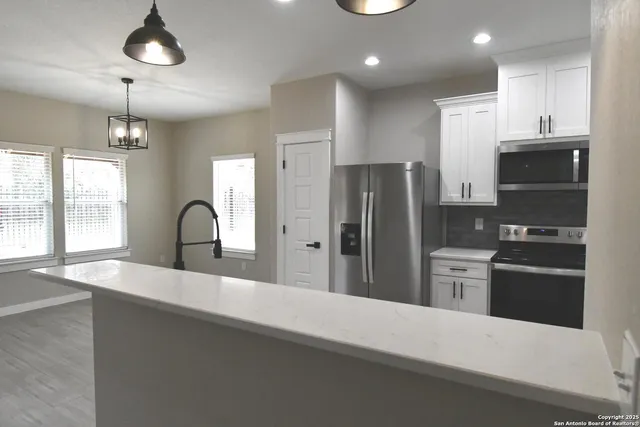 a large kitchen with stainless steel appliances kitchen island a large counter top a stove and a refrigerator