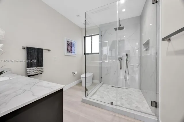 a bathroom with a sink a toilet a mirror and shower