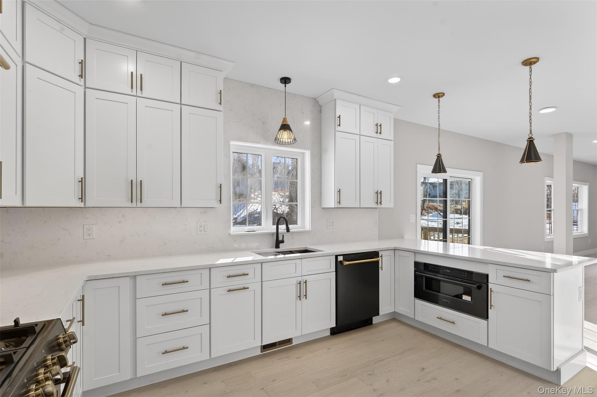 14 Harness Road Goshen, NY 10924 - Photo 13 of 40 Kitchen with a peninsula, white cabinets, decorative light fixtures, black appliances, and tasteful backsplash