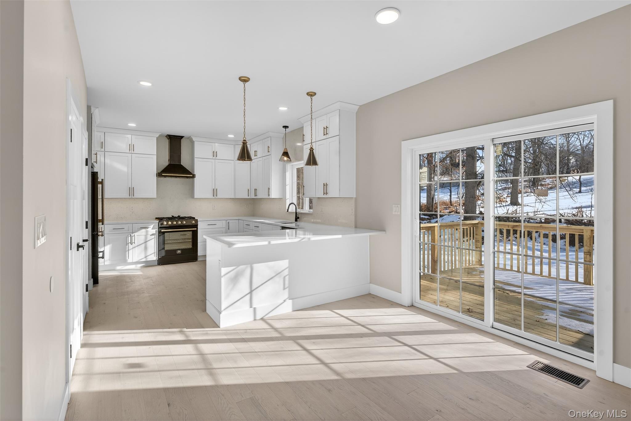 14 Harness Road Goshen, NY 10924 - Photo 15 of 40 Kitchen featuring black gas range, wall chimney range hood, white cabinetry, a peninsula, and light stone countertops