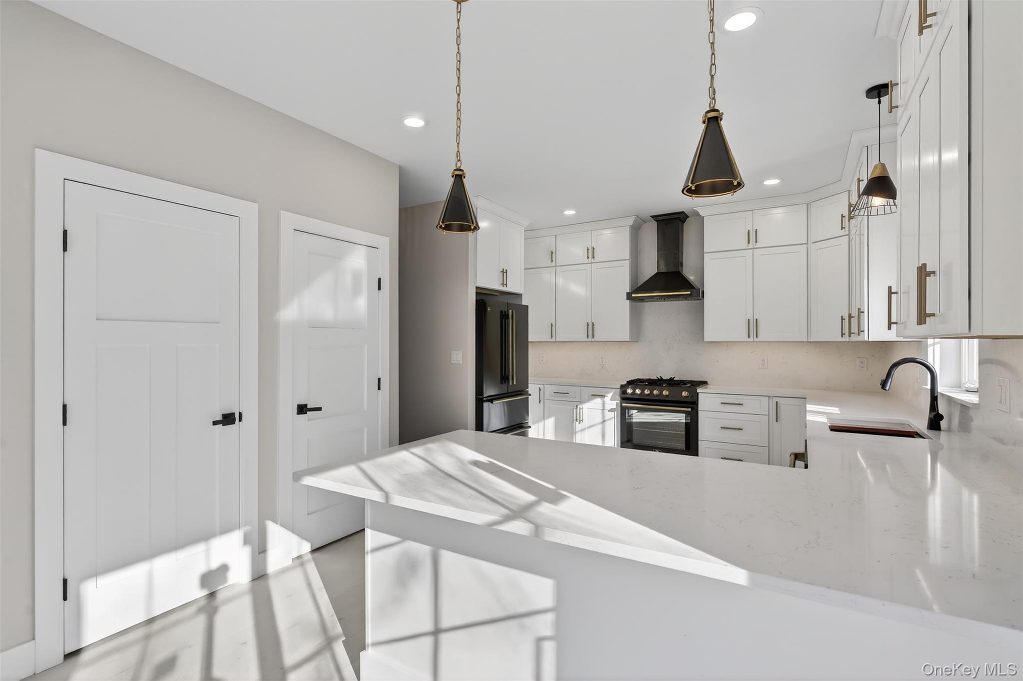 14 Harness Road Goshen, NY 10924 - Photo 17 of 40 Kitchen featuring black gas range oven, high end fridge, a peninsula, wall chimney range hood, and light stone countertops
