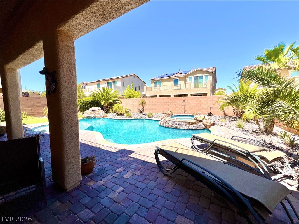 9724 University Ridge Avenue Las Vegas, NV 89149 - Photo 34 of 61 An inviting backyard oasis features a freeform pool and spa, framed by mature palm trees and a paver patio.