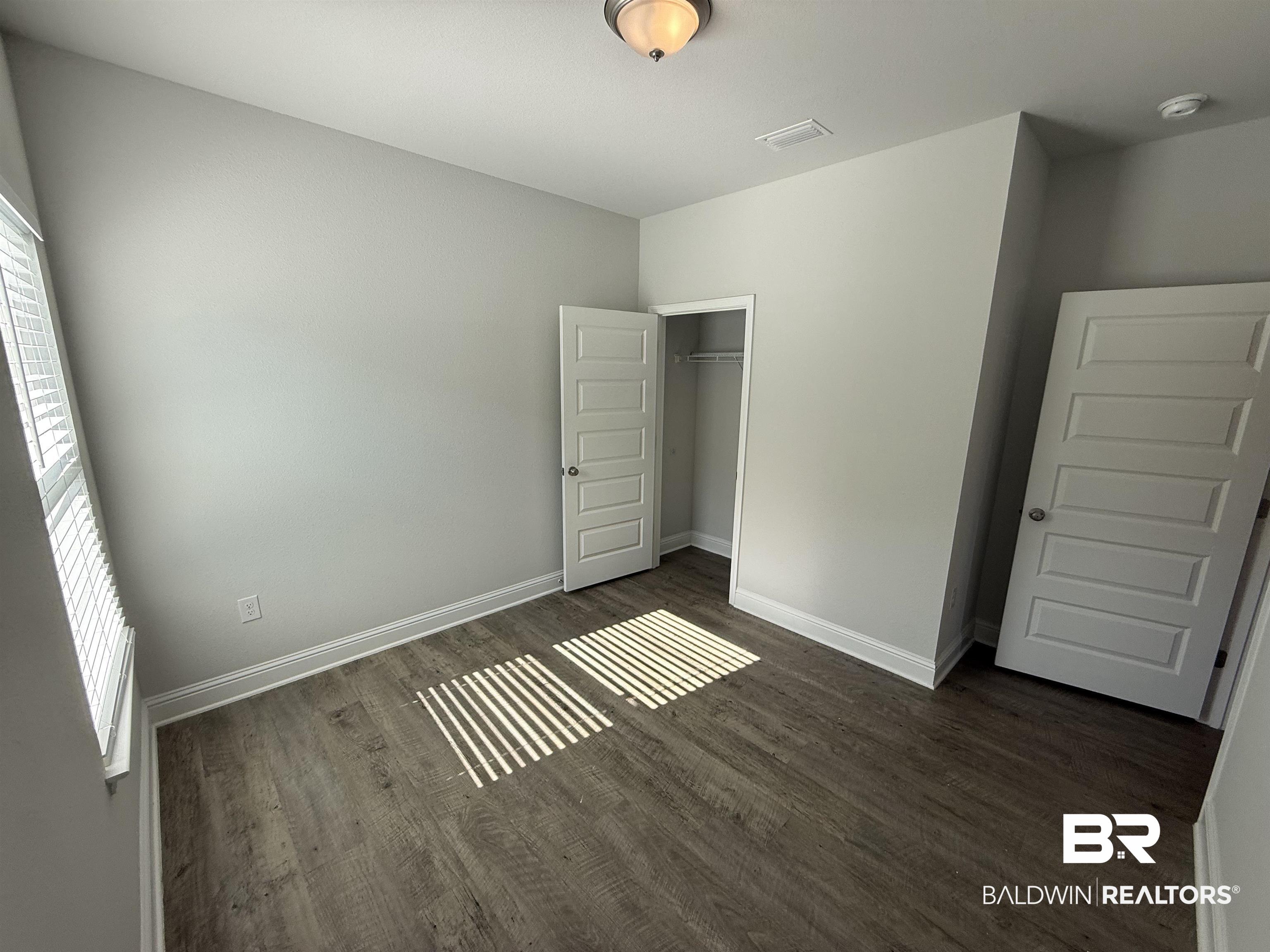 23247 Lieutenant Avenue Foley, AL 36535 - Photo 9 of 47 Room featuring wood-finish flooring, light grey painted walls, white baseboards, and a window with white blinds