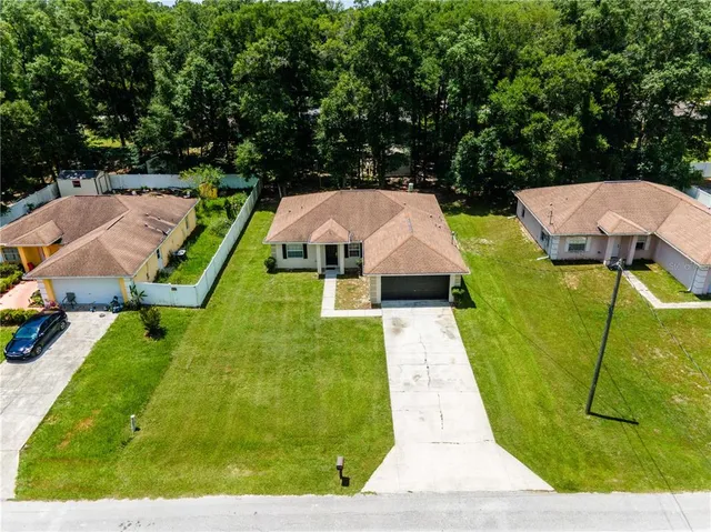 an aerial view of a house with swimming pool and large trees