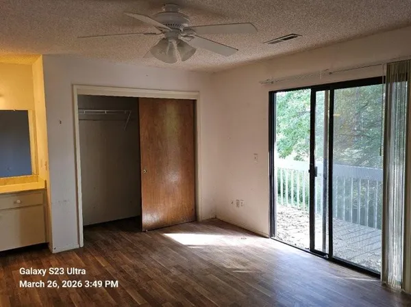 a view of empty room with wooden floor and fan