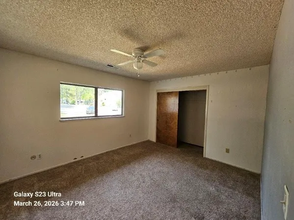 an empty room with windows and fan
